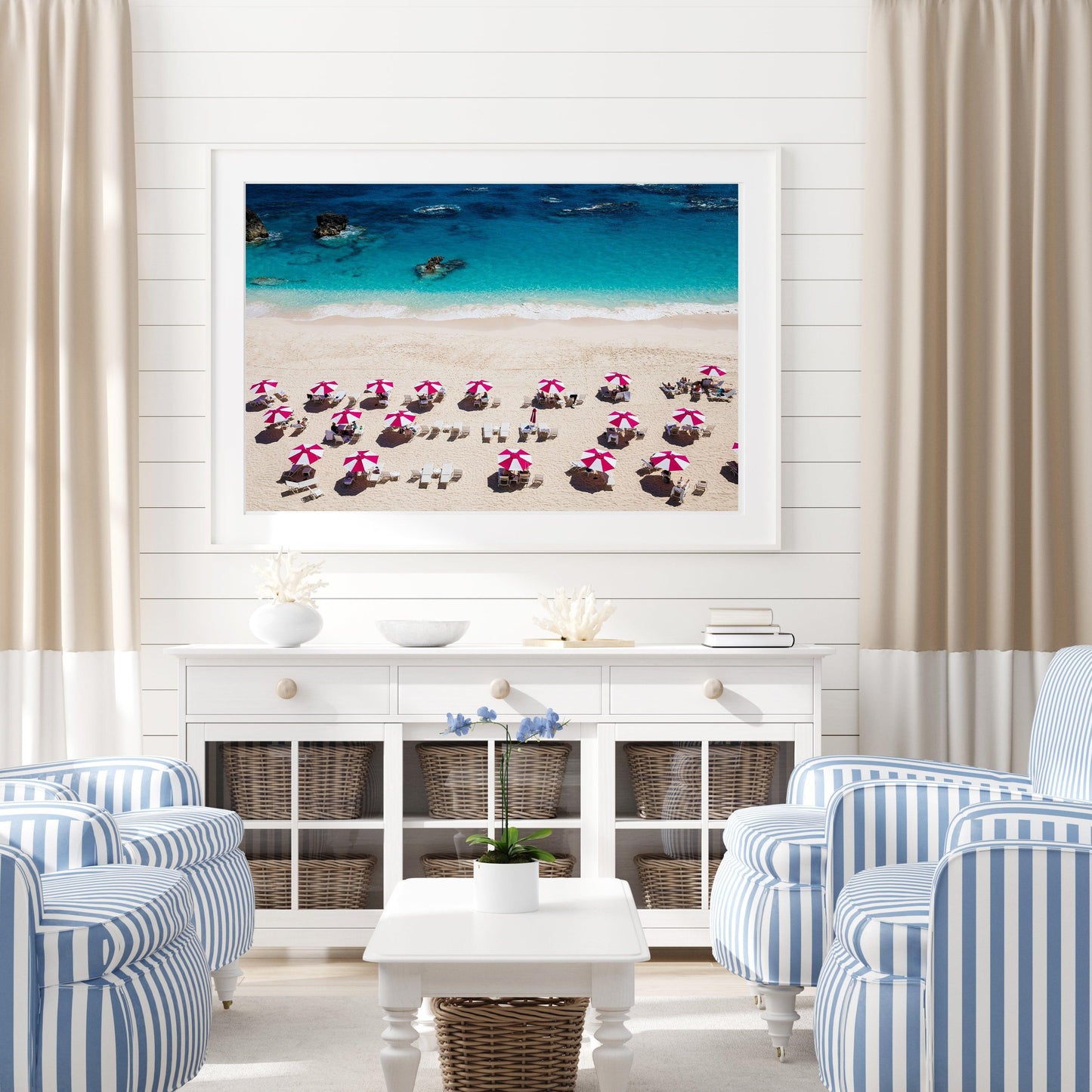 Pink beach umbrellas on Bermuda’s sandy shore with turquoise waters in the background.