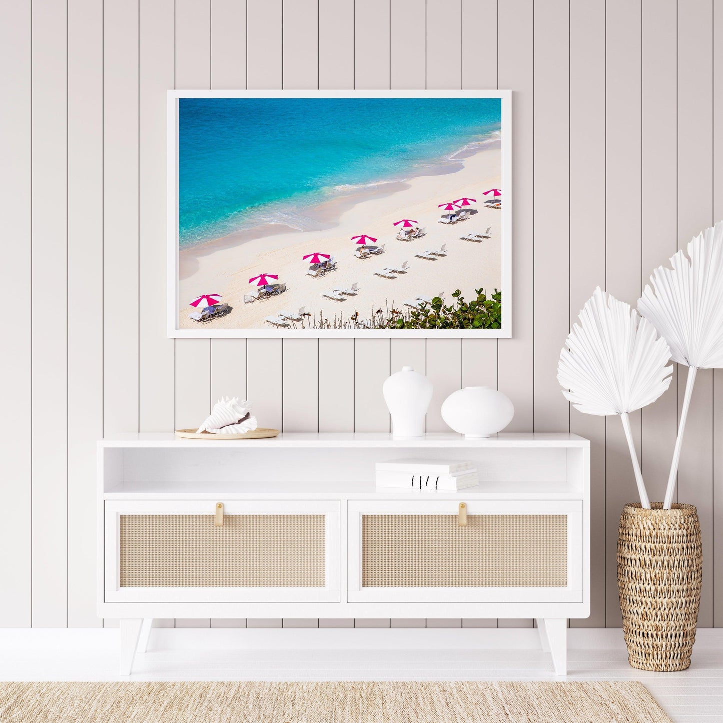 Bright pink beach umbrellas on Bermuda’s sandy shore with turquoise waters in the background.