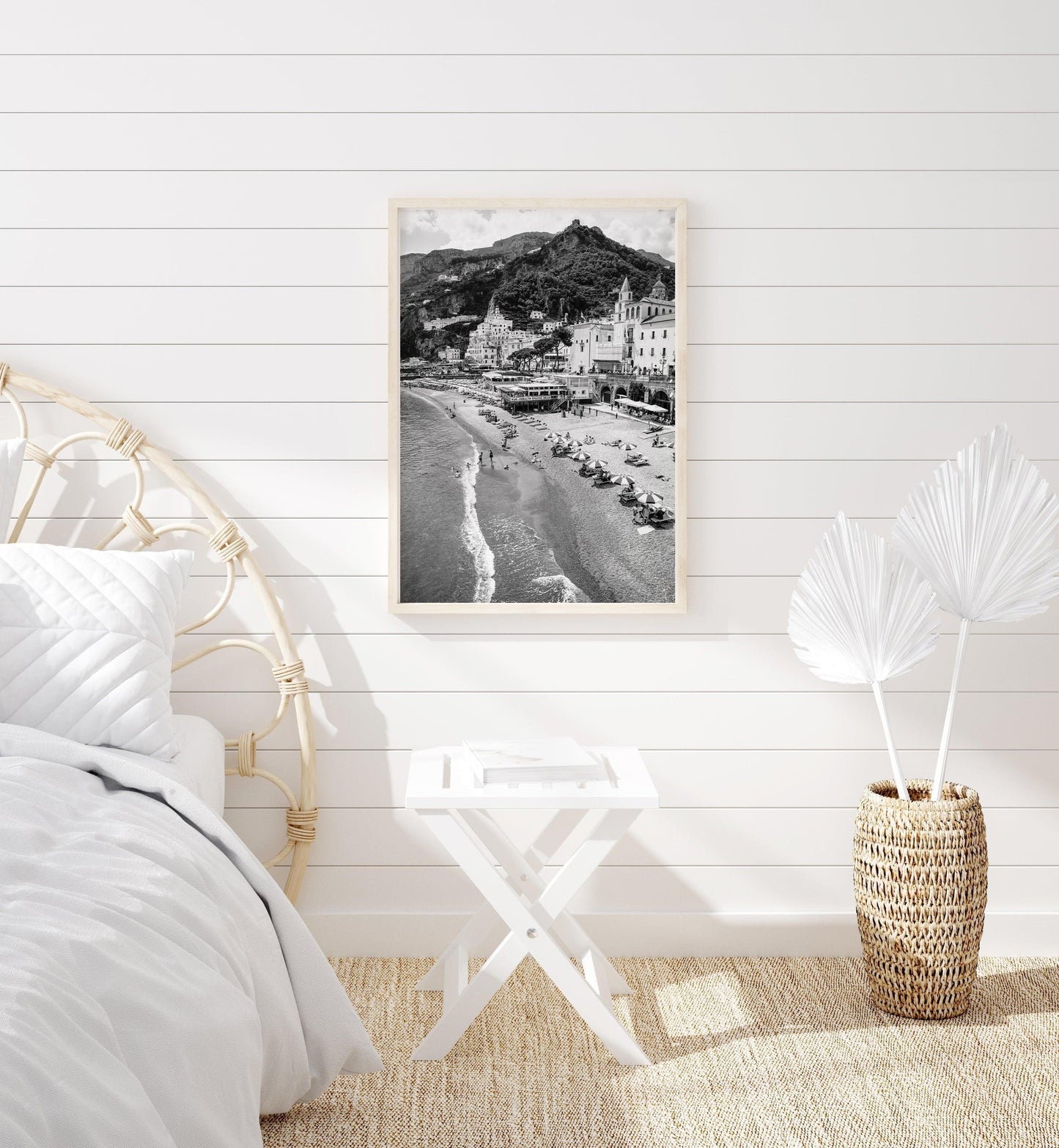 Black and white photograph of Amalfi, Italy featuring beach umbrellas, the city's skyline and scenic cliffside homes.