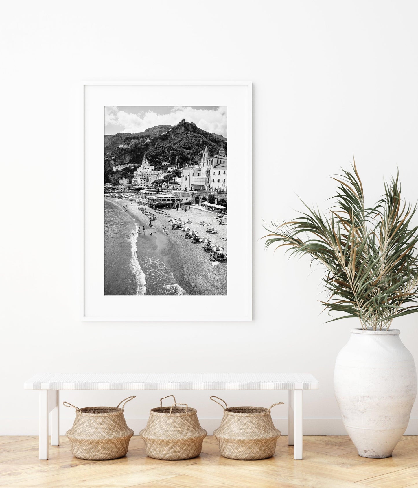 Black and white photograph of Amalfi, Italy featuring beach umbrellas, the city's skyline and scenic cliffside homes.