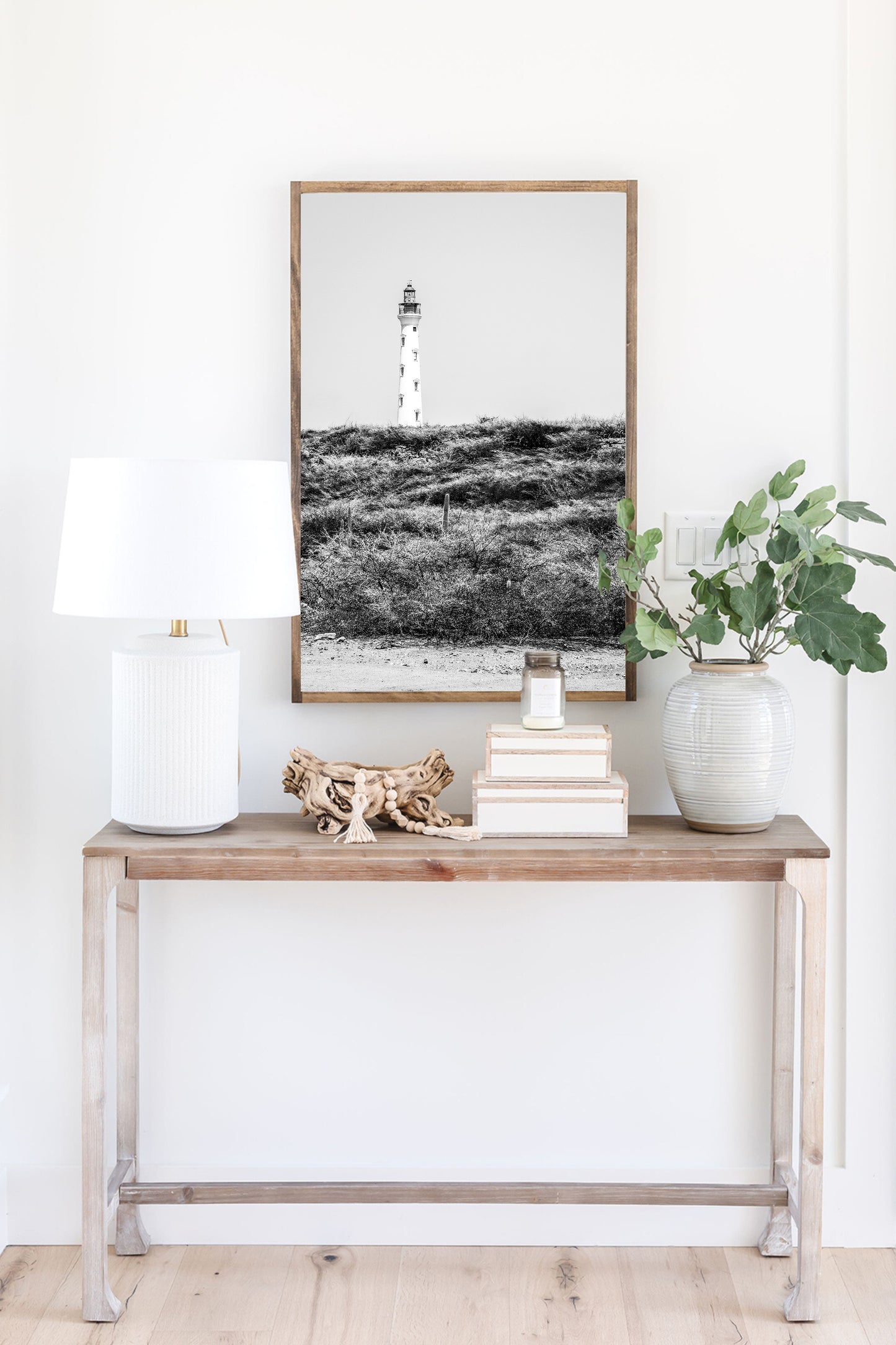 Black and white photo of the Aruba lighthouse standing tall against a bright sky, ideal for beach house decor or coastal wall art.