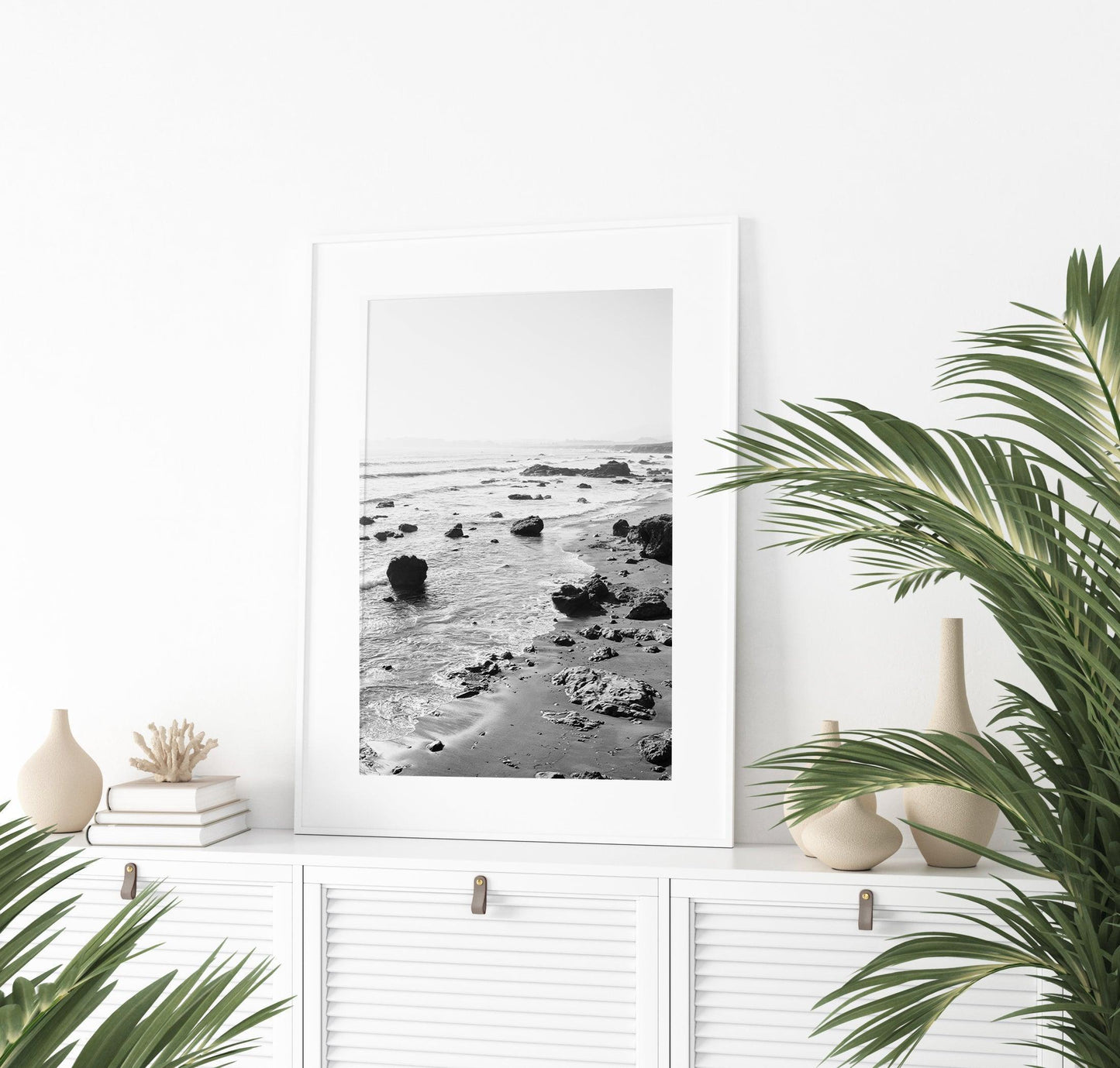 Black and white vertical photo of rocky California coastline with soft waves and distant haze