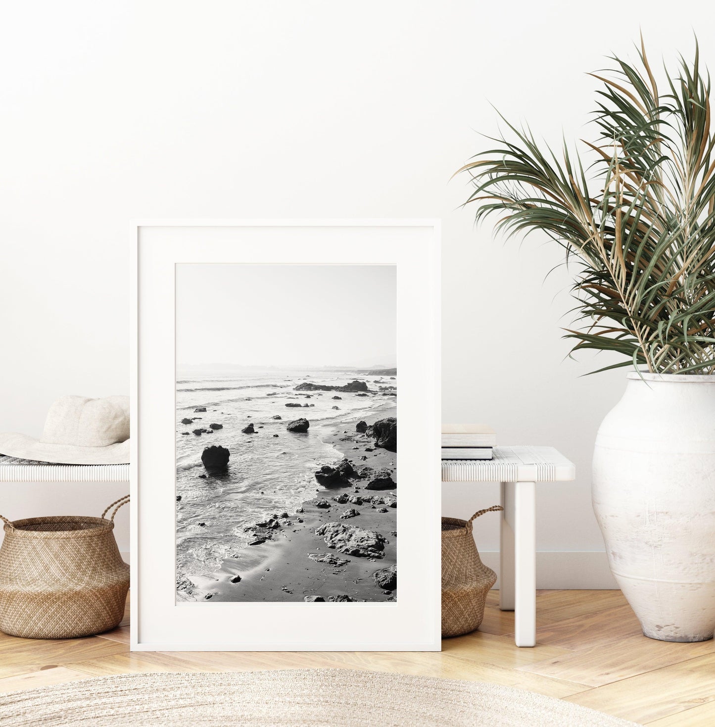 Black and white vertical photo of rocky California coastline with soft waves and distant haze