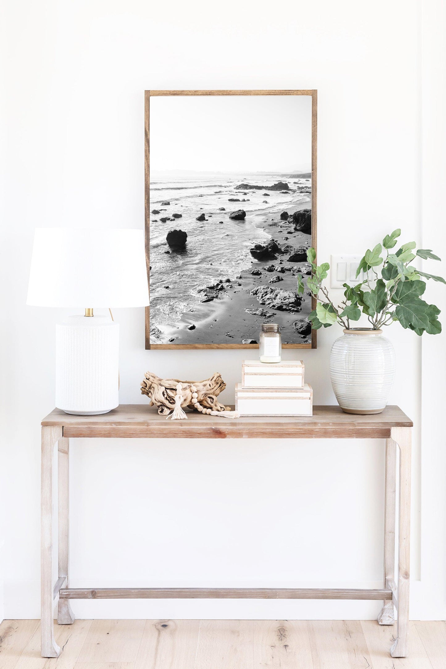 Black and white vertical photo of rocky California coastline with soft waves and distant haze