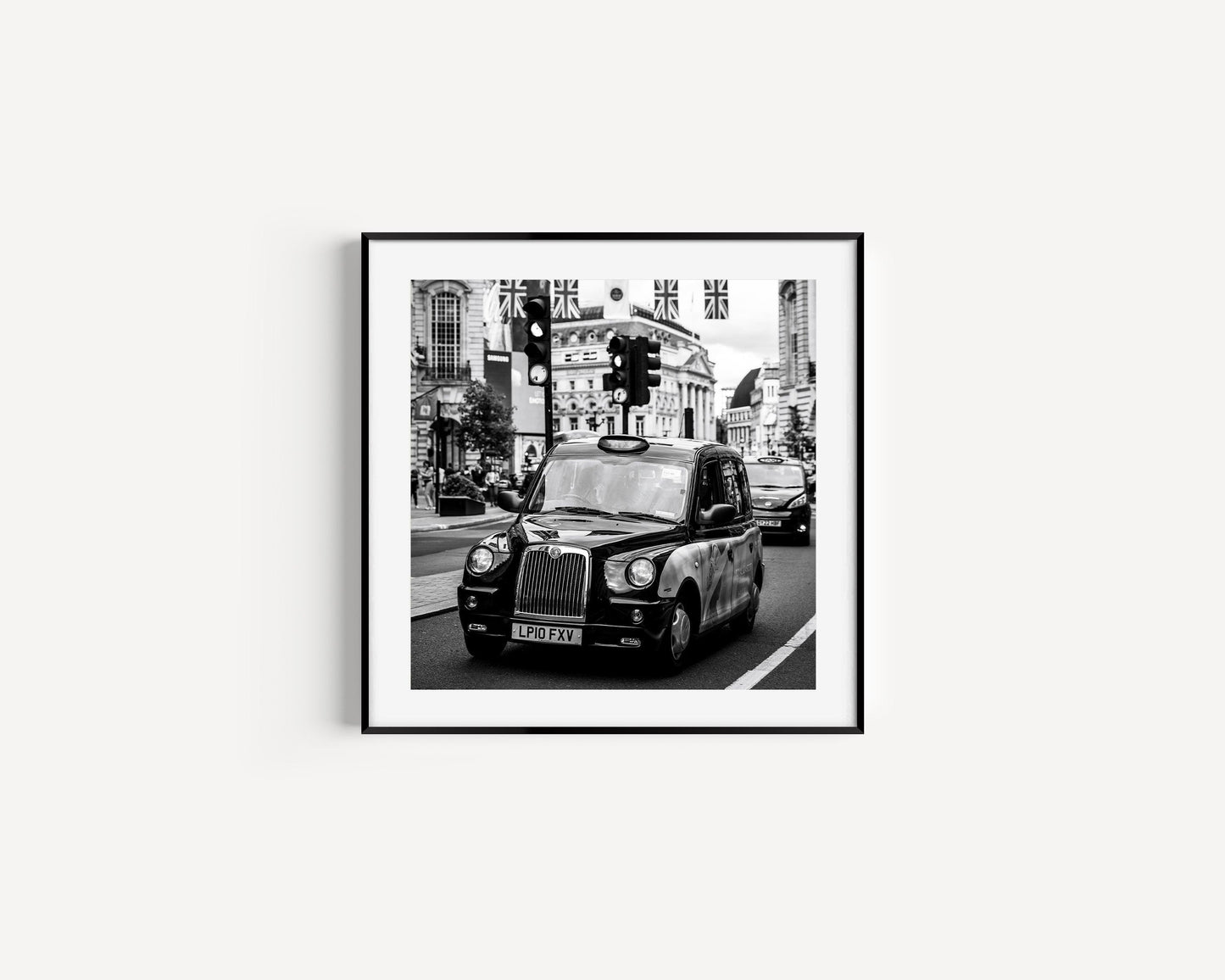 Black and white photograph of a London black cab on city streets, capturing the essence of the city.