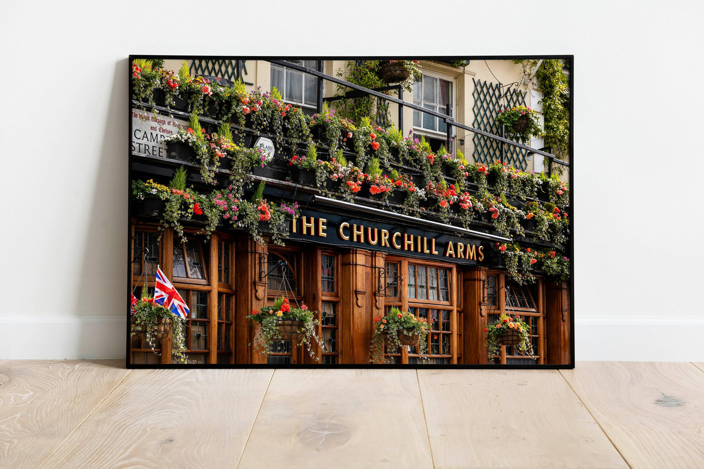 Color photo of The Churchill Arms pub in Notting Hill, London, with hanging flowers and British flag