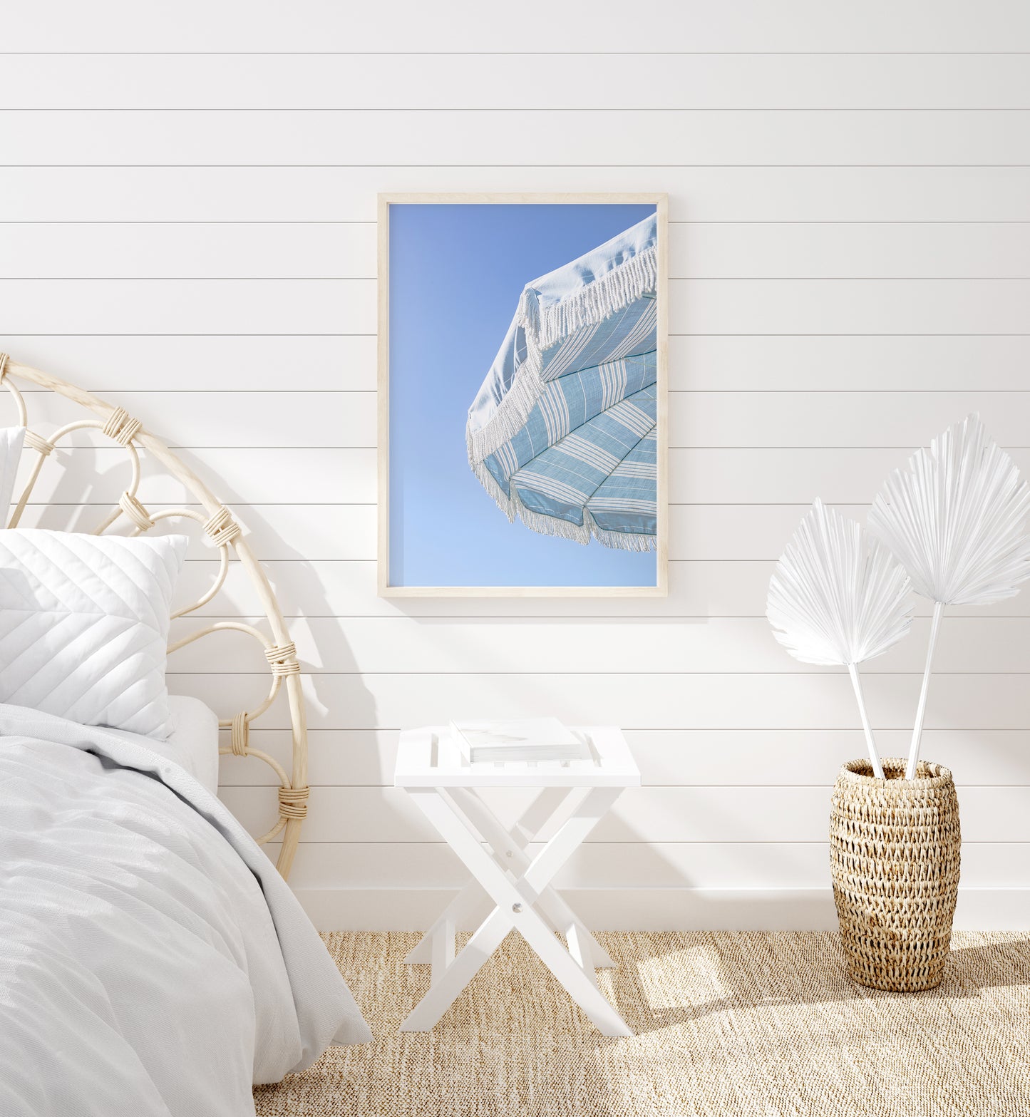 Blue and white striped beach umbrella with fringe set against a clear sky in a minimalist vertical beach photograph.