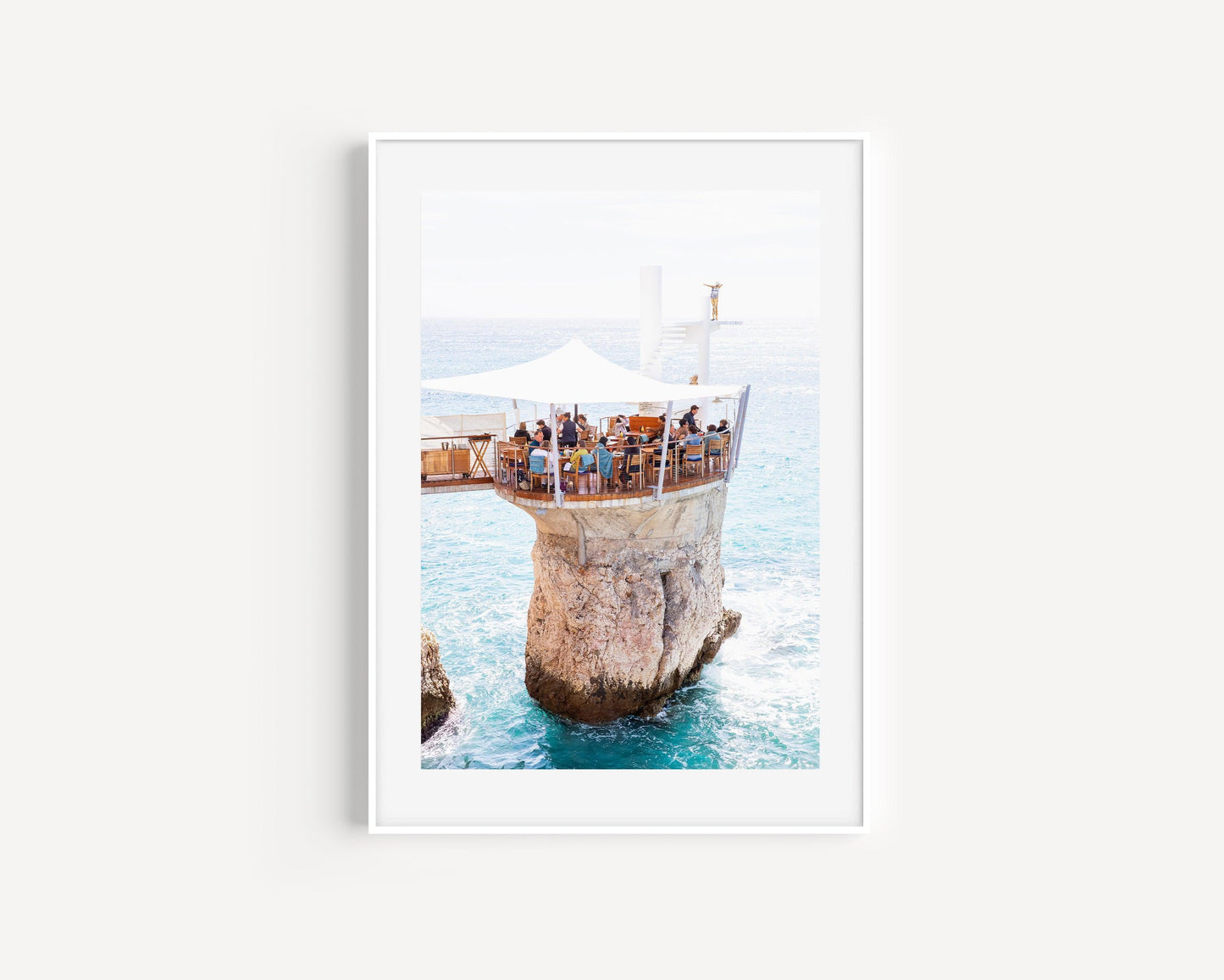 Aerial view of Le Plongeoir restaurant above the sea in Nice, France, with bright turquoise Mediterranean water and coastal cliffs.