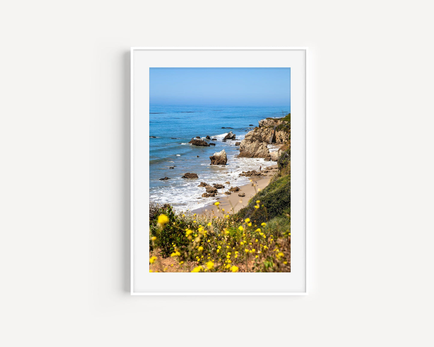Vertical California coastal photo of El Matador State Beach with yellow wildflowers, rocks, and blue ocean