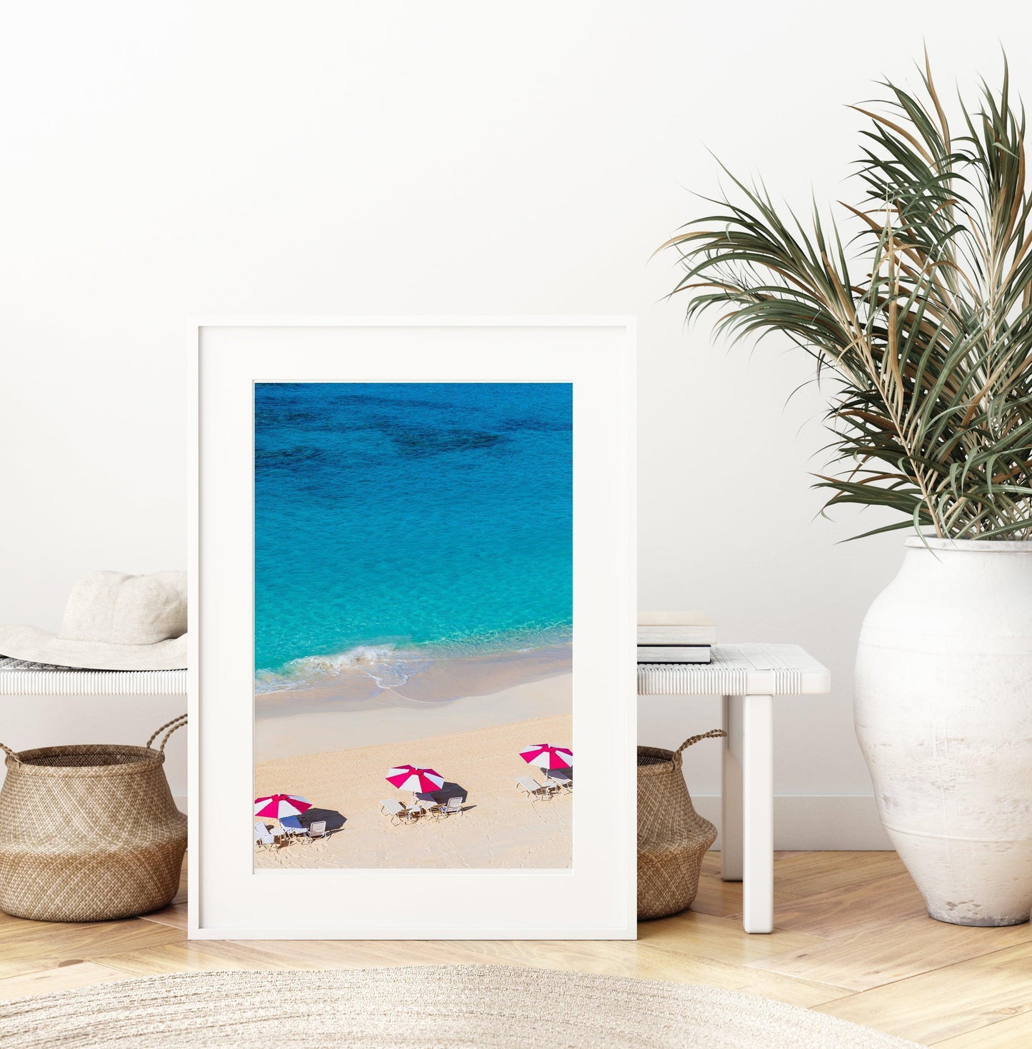 Vertical aerial view of three pink beach umbrellas on a Bermuda shoreline with turquoise ocean