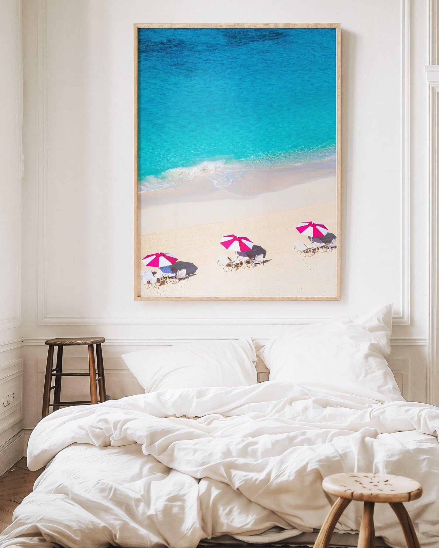 Vertical aerial view of three pink beach umbrellas on a Bermuda shoreline with turquoise ocean