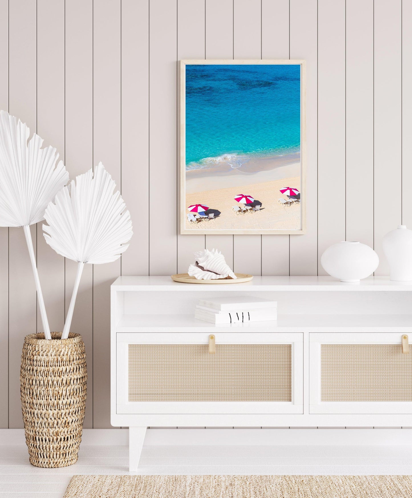 Vertical aerial view of three pink beach umbrellas on a Bermuda shoreline with turquoise ocean