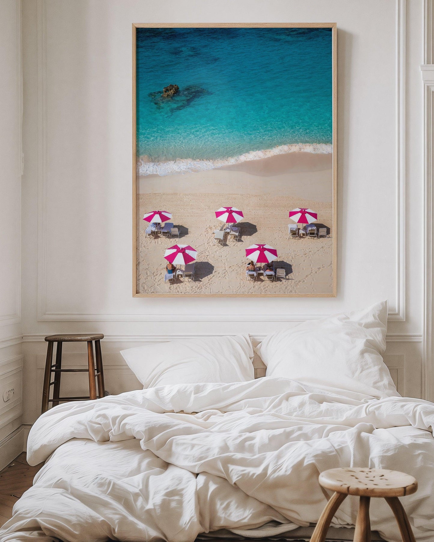 Aerial view of five pink beach umbrellas on a Bermuda shoreline with turquoise water