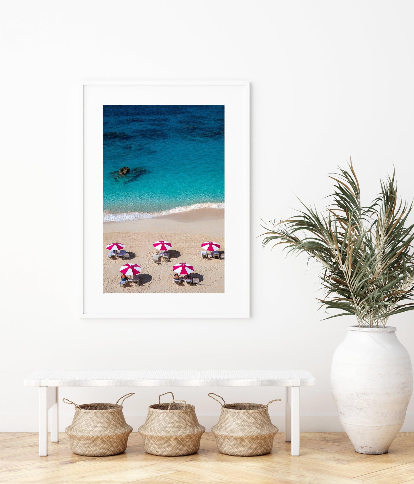 Aerial view of five pink beach umbrellas on a Bermuda shoreline with turquoise water