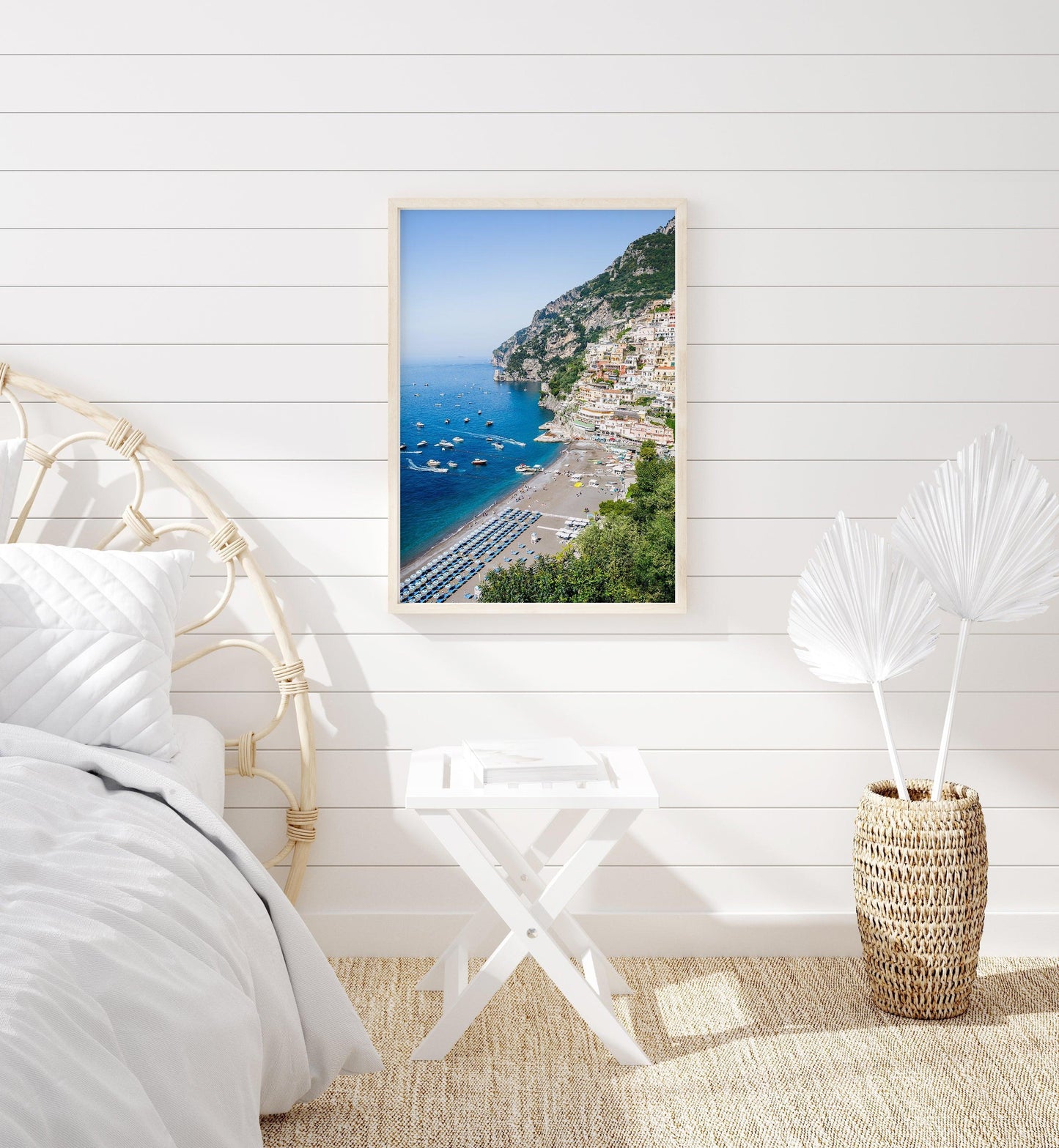 Colorful buildings stacked along the cliffs of Positano rise above a beach filled with striped umbrellas and sunbathers on the Amalfi Coast in Italy.