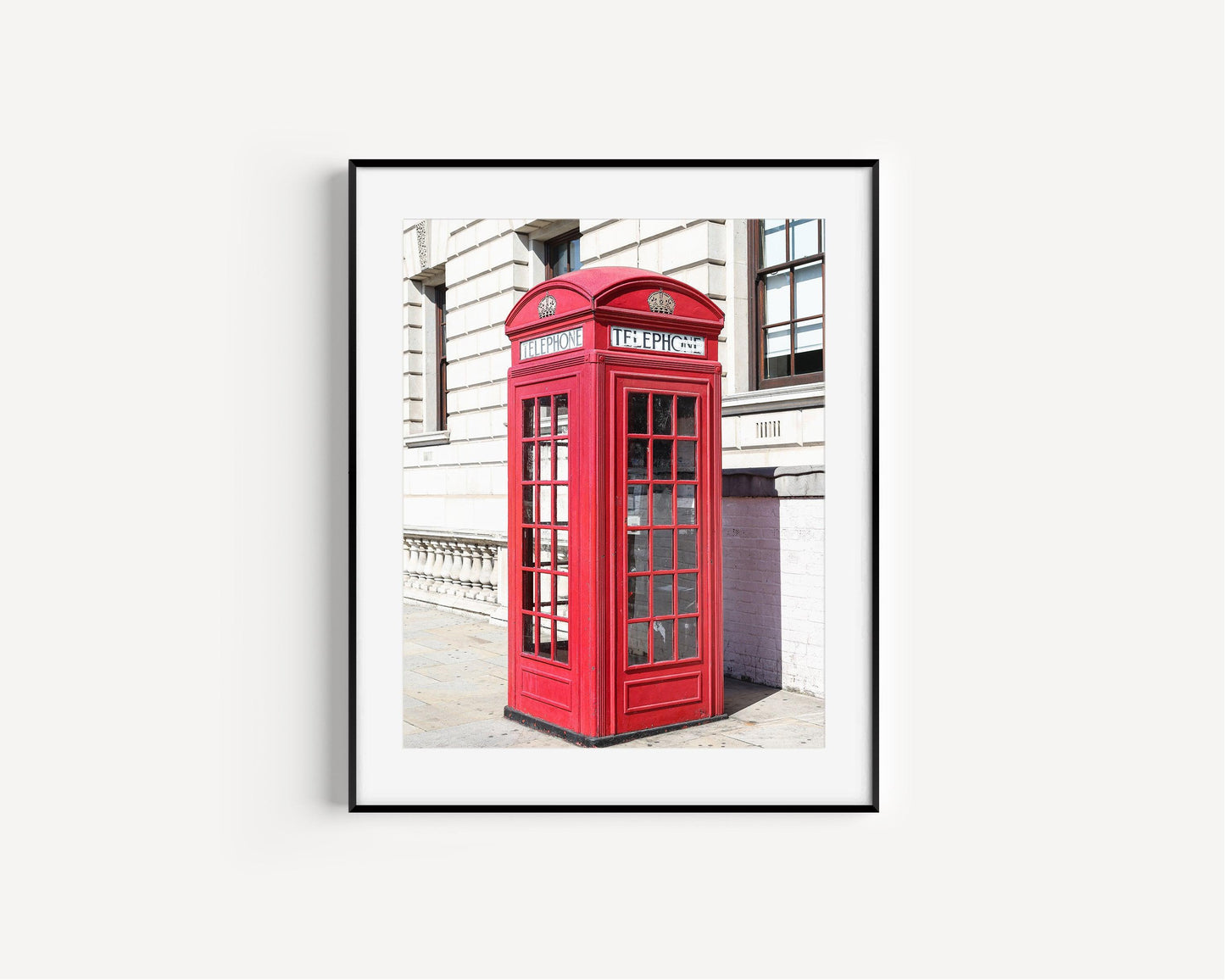 A classic red telephone booth stands out in vivid color against a black and white London street scene. A bold and graphic British landmark print for home or office decor.
