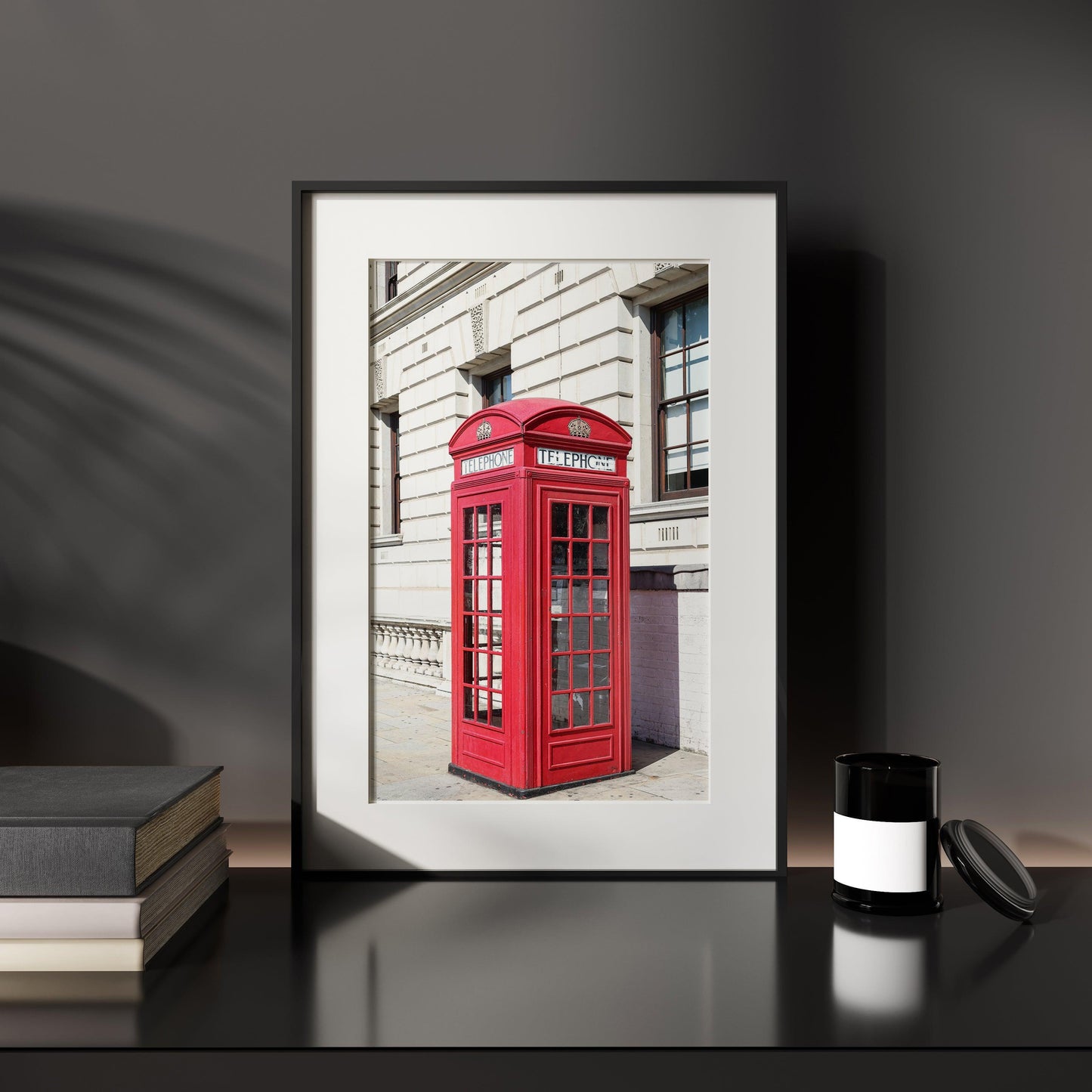 A classic red telephone booth stands out in vivid color against a black and white London street scene. A bold and graphic British landmark print for home or office decor.
