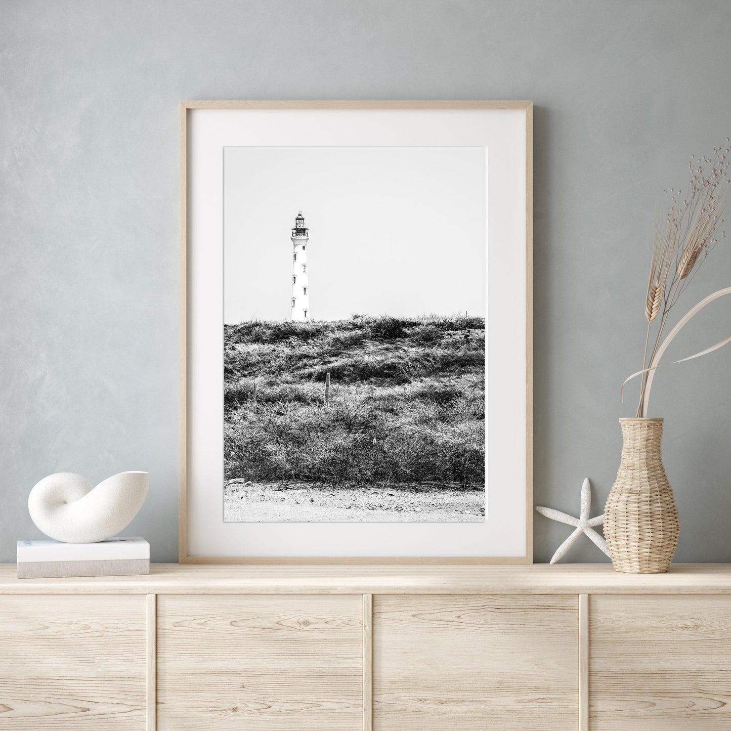 Black and white photo of the Aruba lighthouse standing tall against a bright sky, ideal for beach house decor or coastal wall art.