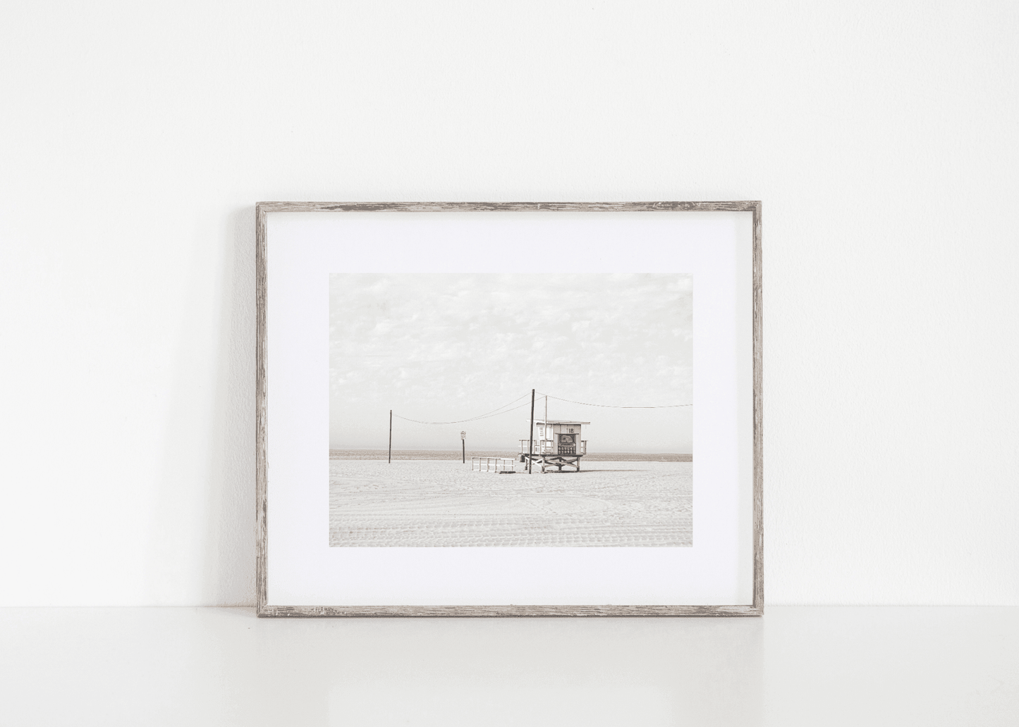Black and white beach photo of lifeguard tower on California sand – minimalist coastal wall art