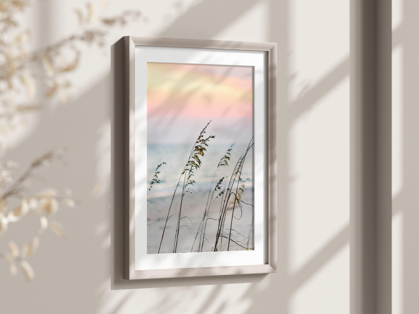 Sea oats on a sandy beach at sunset with soft pastel sky and ocean in the background