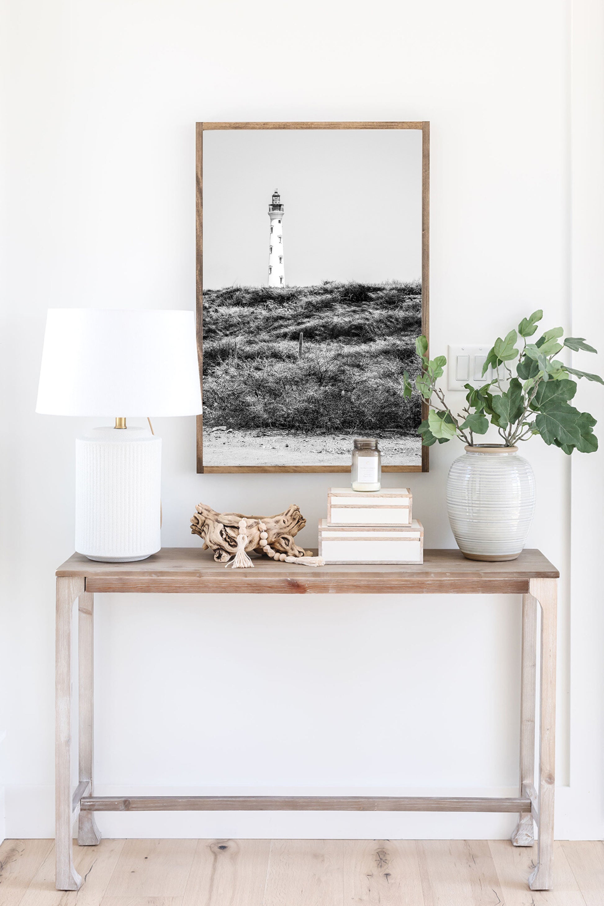 Black and white photo of the Aruba lighthouse standing tall against a bright sky, ideal for beach house decor or coastal wall art.