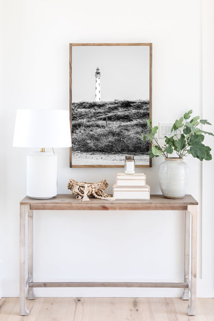 Black and white photo of the Aruba lighthouse standing tall against a bright sky, ideal for beach house decor or coastal wall art.