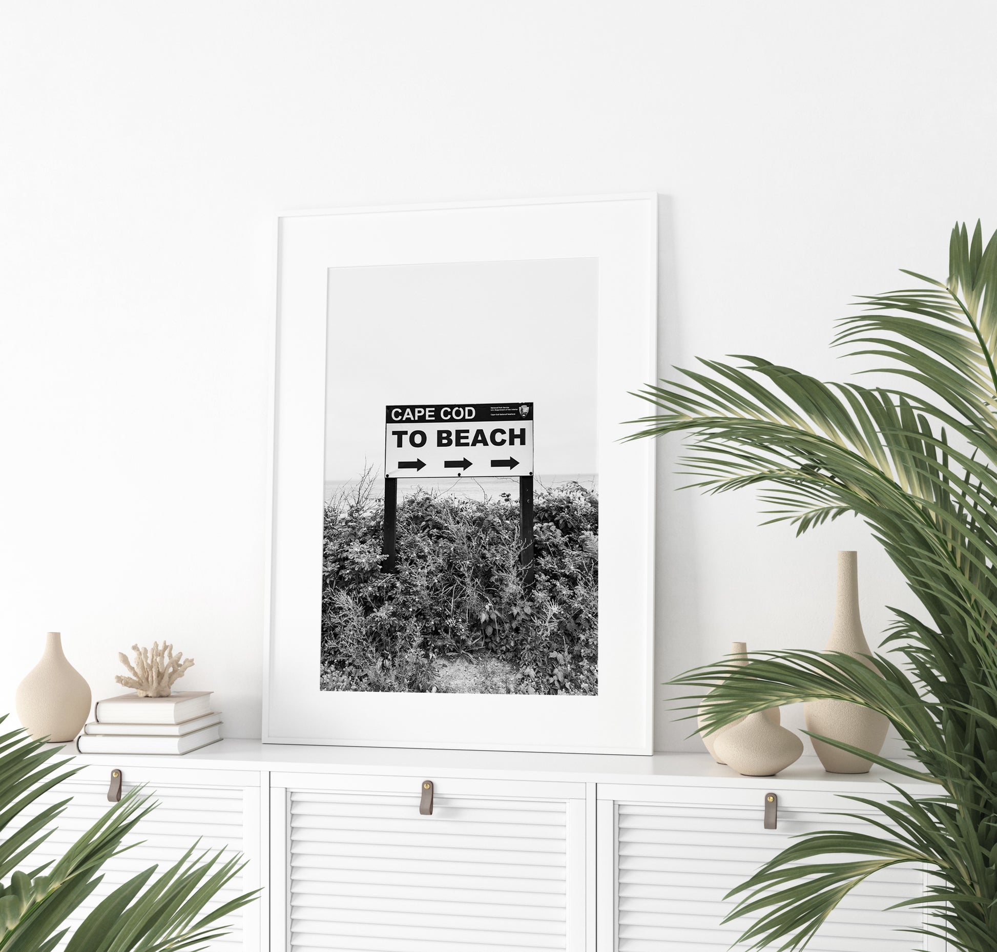 Black and white photography print of a vintage-style sign reading 'Cape Cod Beach This Way' with an arrow, set against a clear sky.