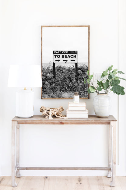 Black and white photography print of a vintage-style sign reading 'Cape Cod Beach This Way' with an arrow, set against a clear sky.
