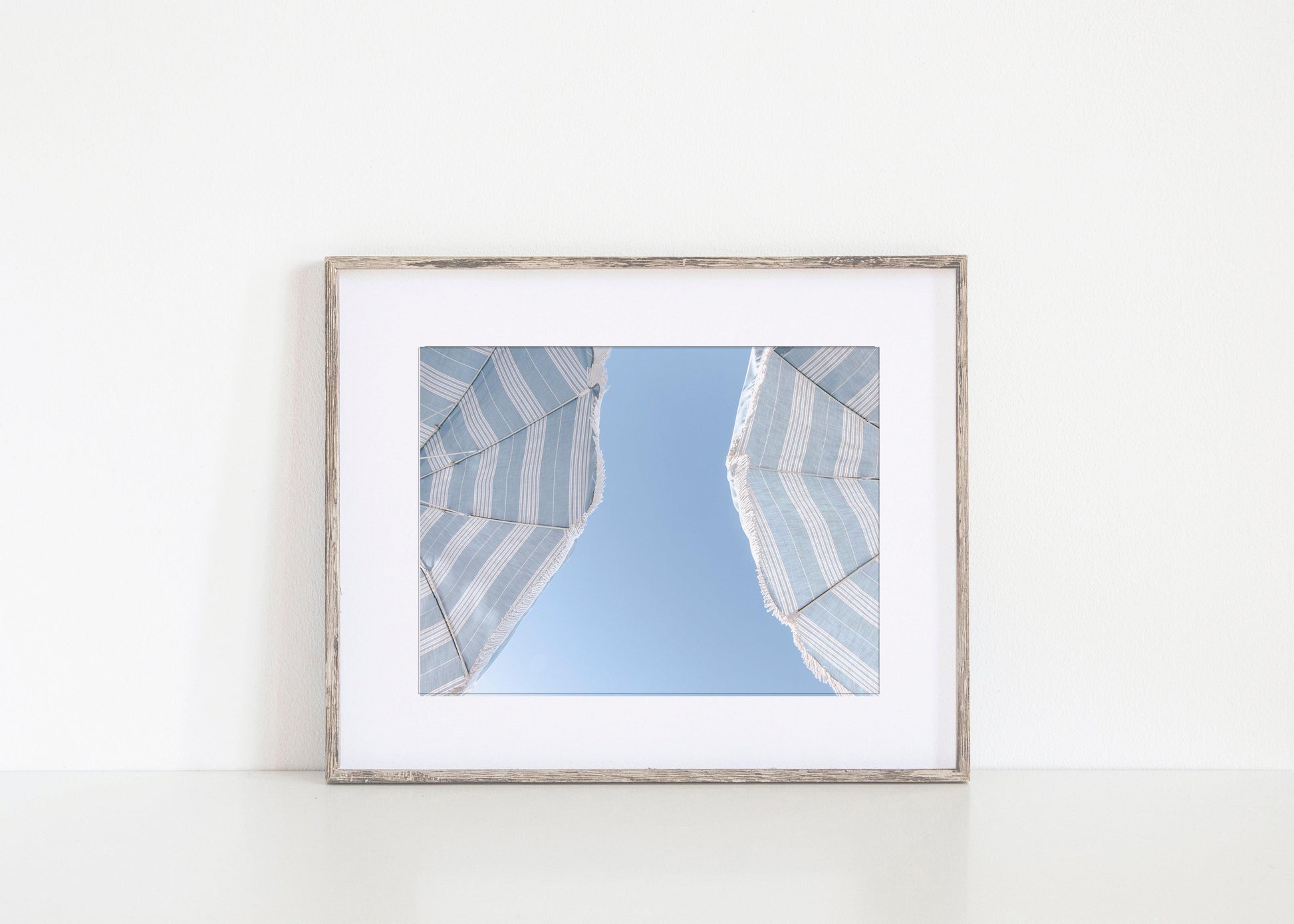 Blue striped beach umbrellas against a clear sky – horizontal coastal summer print