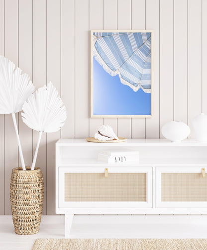Vertical photo of striped blue beach umbrella with fringe and bright blue sky – coastal summer wall art