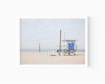 Lifeguard tower on Santa Monica Beach with soft sand and blue sky – coastal California photography print.