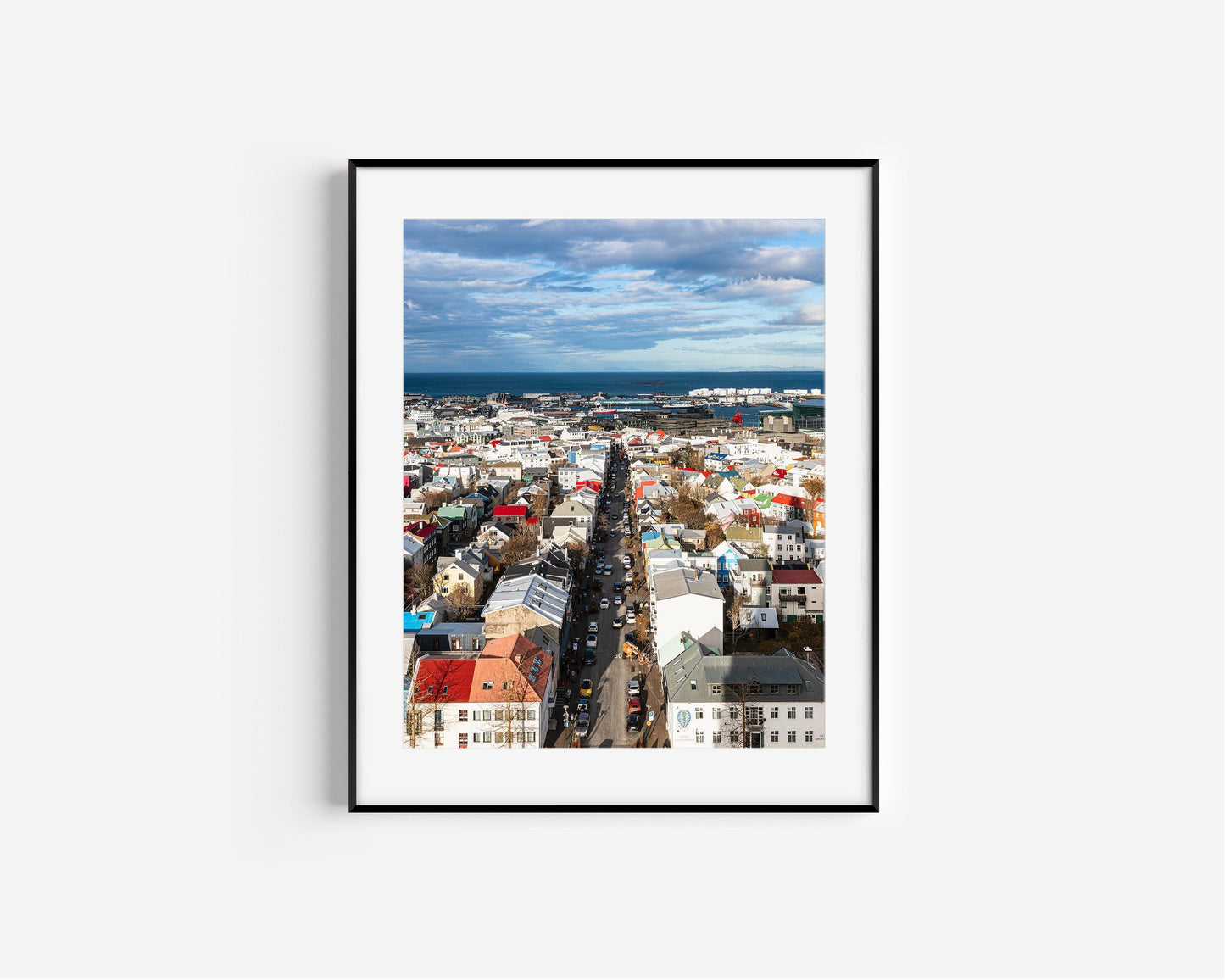 Colorful Reykjavik skyline on a clear day, showing a Nordic cityscape with vibrant rooftops, downtown buildings, and the North Atlantic in the background. Vertical Iceland photography print.
