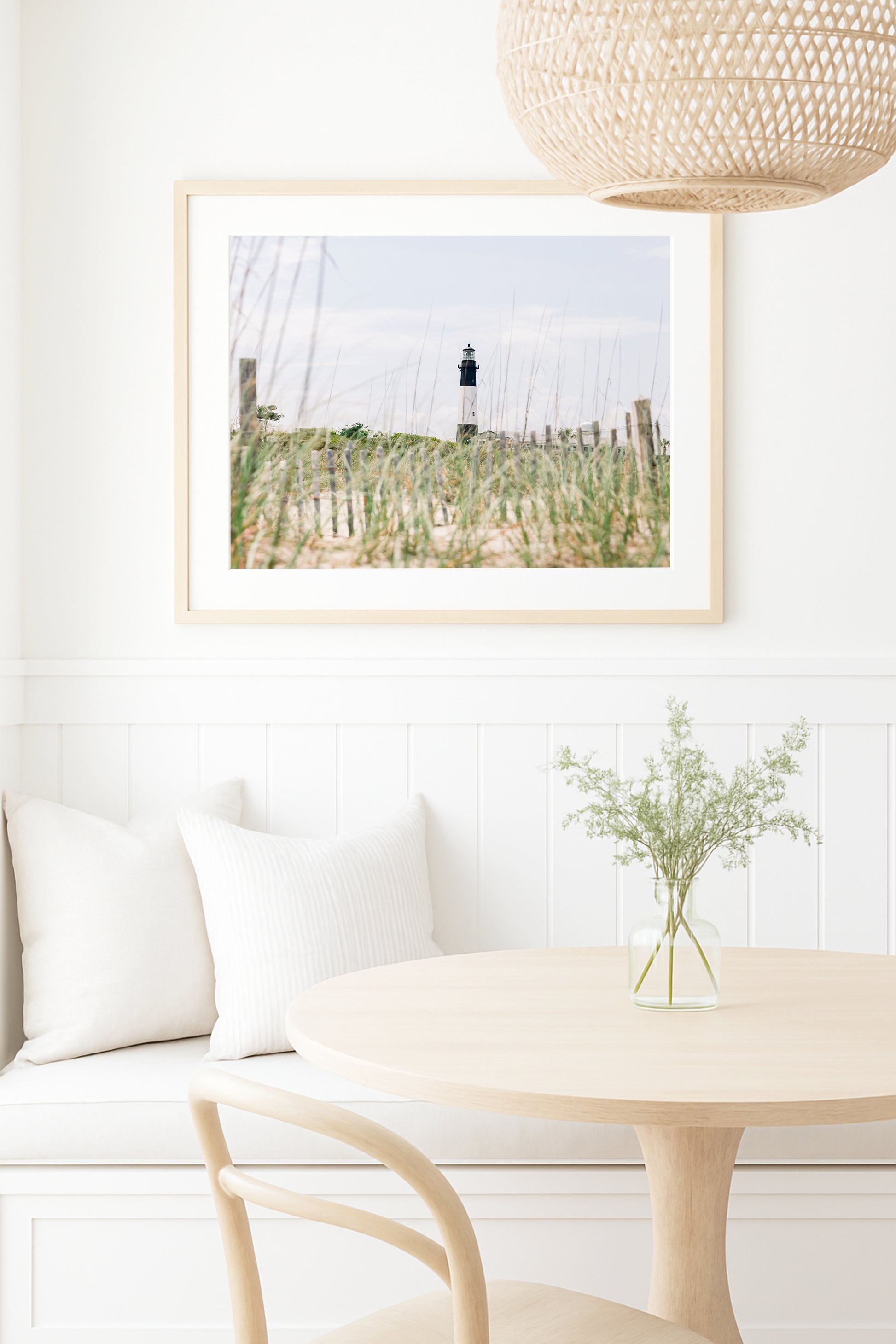 Tybee Island Lighthouse in Georgia, viewed through beach grass with sand dunes and blue sky in the background.