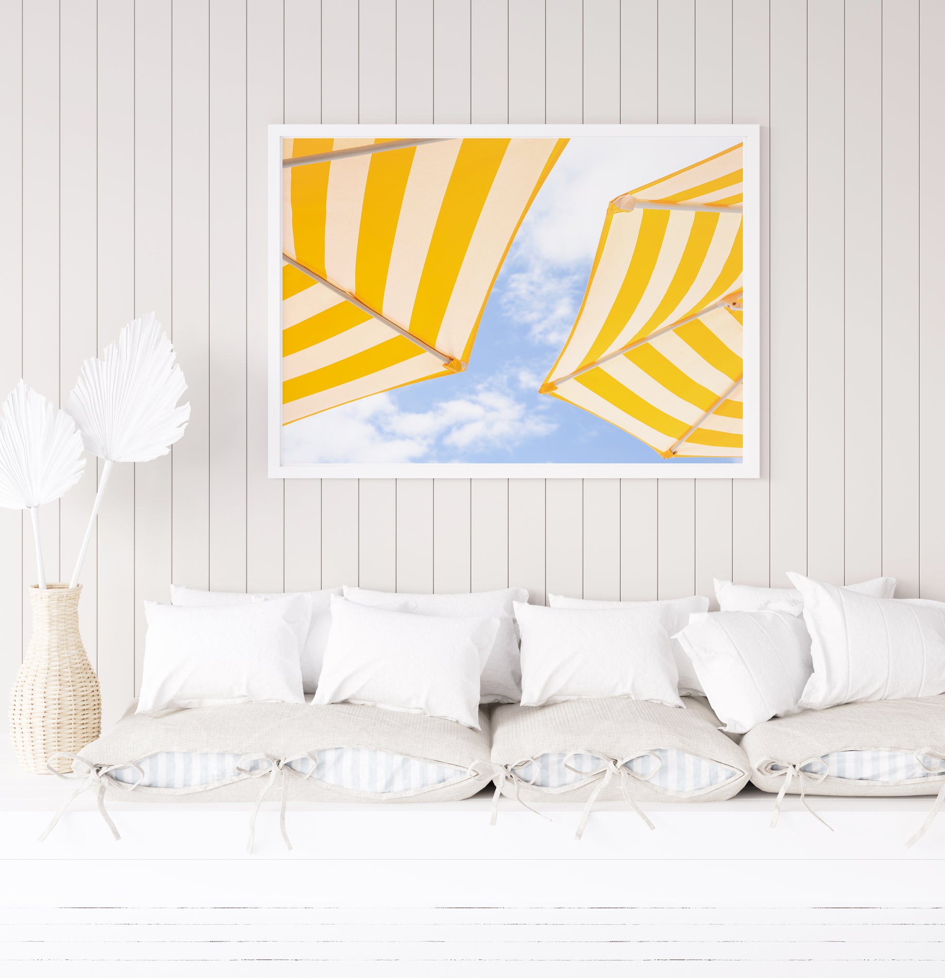 Yellow and white striped beach umbrellas set against a bright blue sky with scattered clouds; minimalist beach photography evoking a sunny Amalfi Coast vibe.